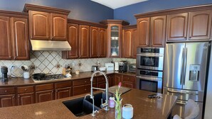 Une cuisine moderne avec des meubles en bois, des appareils en acier inoxydable et des plans de travail en granit.