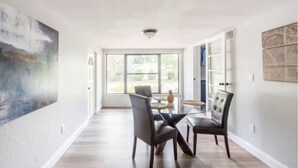 Un vaste espace dédié à la salle à manger, avec une table en verre, deux chaises et une vue dégagée grâce à de grandes fenêtres.