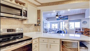 A kitchen with a built-in microwave, stove, and cabinets. There is a dining area with a table and chairs visible through an open doorway.
