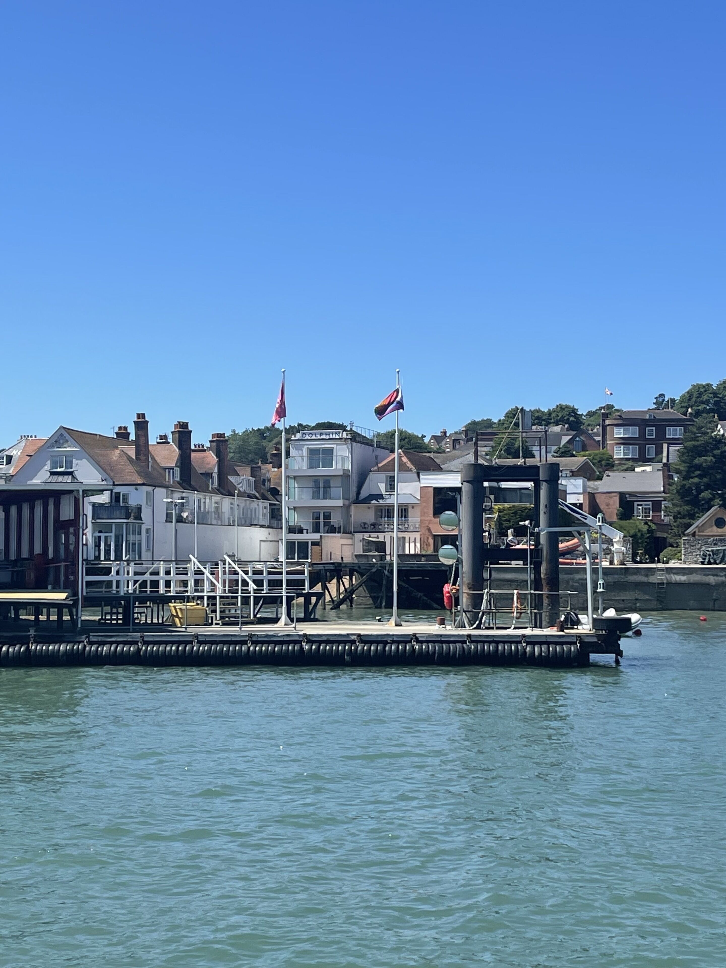 Une jetée donnant sur le port, avec un bâtiment portant l’inscription « DOLPHIN » et deux drapeaux.