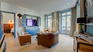Una sala moderna con un sofá, sillones, televisor y un comedor.
