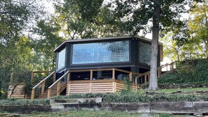 Een modern huis met een grote glazen gevel, een houten terras en een trap naar de ingang.