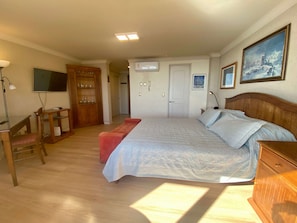 Un dormitorio con cama, escritorio, silla, armario y televisor.