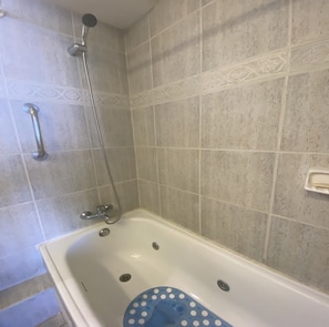 Un baño con bañera, ducha y barra de apoyo.