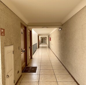 A hotel corridor with doors, a fire extinguisher, and a welcome mat. - Oceanfront Studio - A/C, Views, Pool & Parking (Viña del Mar)