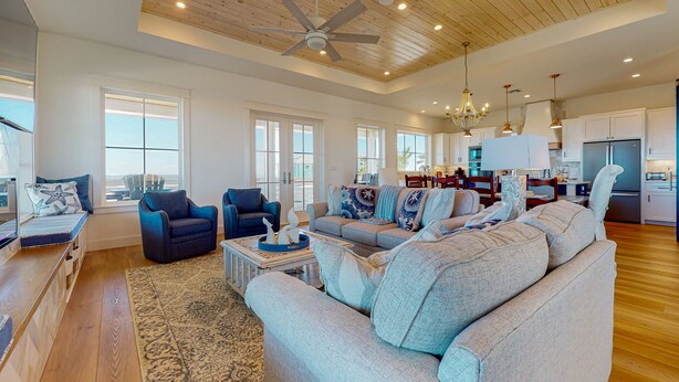 A spacious living room with a large sofa, two armchairs, and a coffee table. There is a dining area with a table and chairs, and a kitchen with modern appliances. - Gulf Views, Private Heated Pool, Golf Cart Included, Boardwalk to the Beach (Port Aransas)