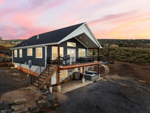Ein zweistöckiges Haus mit Balkon, überdachter Terrasse und Whirlpool.