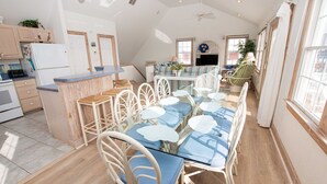 A spacious kitchen with a dining area, featuring a glass table and white chairs. - Oceanside, Private Pool, Hot Tub, Ocean Views (Rodanthe)