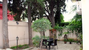 A patio area with a table and chairs, surrounded by potted plants and trees. - Darchi Hotel (Tbilisi)