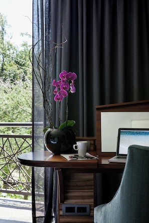 A room with a desk, a laptop, a cup, and a vase with flowers. - Seven Villa Hotel and Spa (Johannesburg)