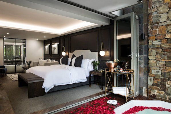 Un dormitorio moderno con una cama grande, una pared de acento de piedra y vistas al exterior.