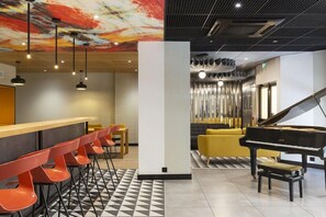A modern lounge area with a bar, red chairs, a piano, and a staircase. - Ibis Marseille Centre Prefecture (Marseille)