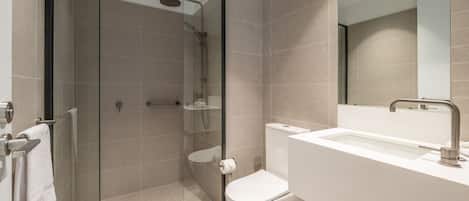 Een moderne badkamer met een douchecabine van glas, een wit wastafelmeubel en een toilet.