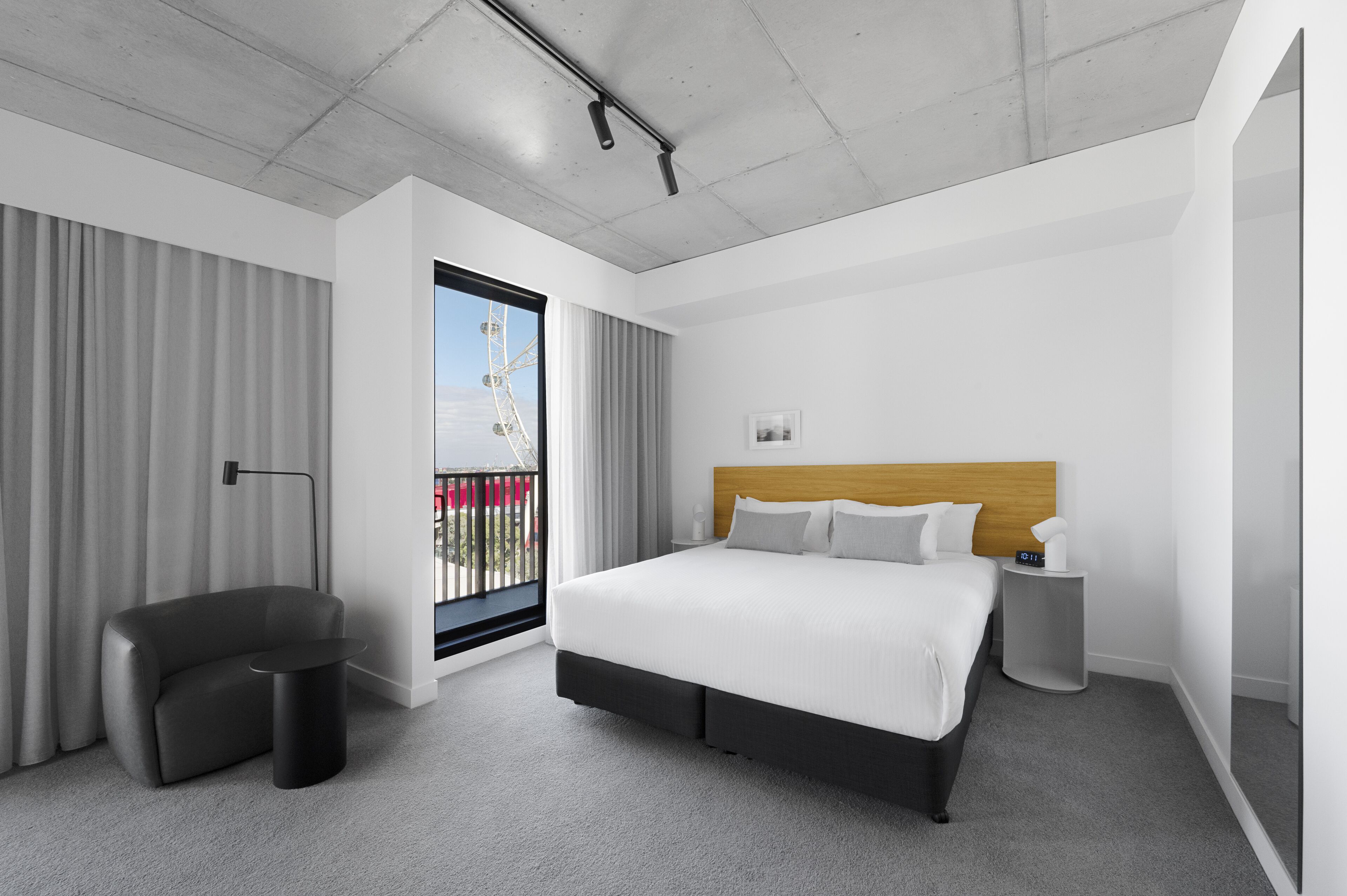 Habitación de hotel moderna con una cama grande, un escritorio, una silla y vistas a una noria.
