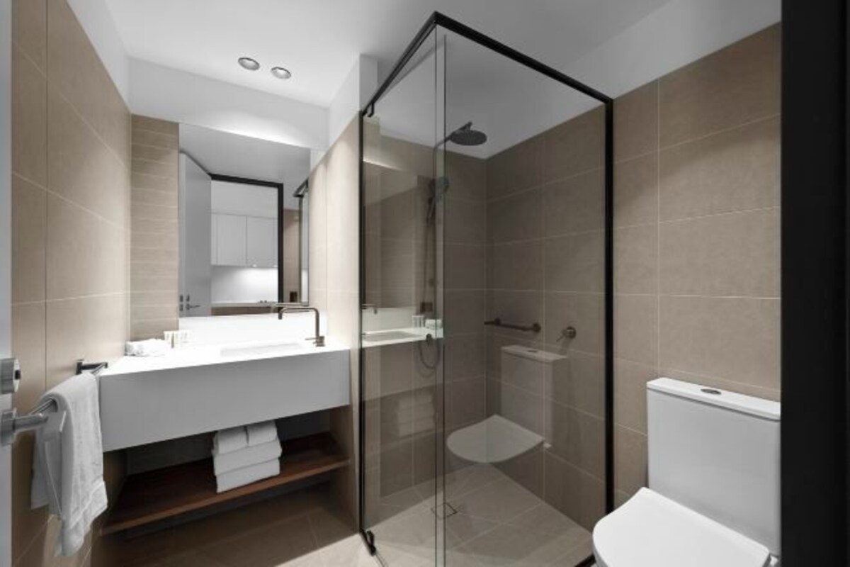 Een moderne badkamer met een douchecabine van glas, een witte wastafel en een toilet.