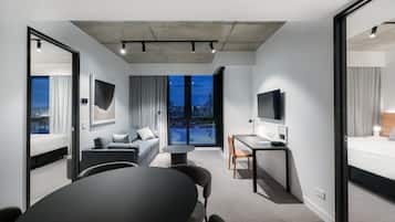 Ett modernt hotellrum med en stor säng, en soffa, ett matbord och en TV.