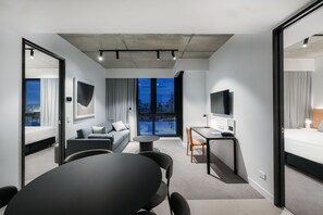 Een moderne hotelkamer met een groot bed, een bank, een eettafel en een televisie.