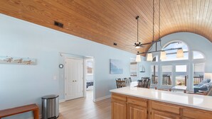 A spacious kitchen with wooden cabinets, a large island, and a view of the outdoors through the windows.