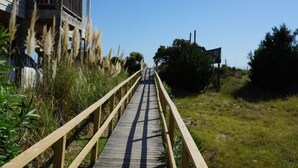 Un muelle de madera que conduce a un edificio con balcón.