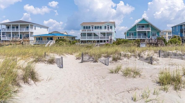 Una propiedad frente a la playa con varias casas, una playa de arena y una zona de dunas con césped.