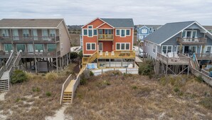 A beachfront property with multiple houses connected by wooden walkways. - Hobbs Realty - Enjoy sunny "Beach Daze" in your private pool and hot tub in this oceanfront home. (Holden Beach)