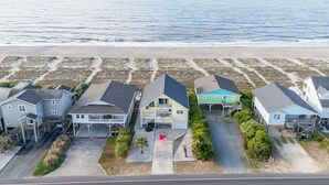Una zona residencial costera con casas que tienen porches y una playa al fondo.