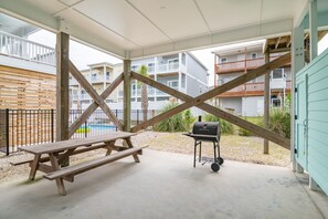 Un espacio al aire libre cubierto con una mesa de picnic y una parrilla, rodeado de edificios.