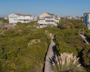A coastal residential area with multiple two-story houses featuring balconies and a wooden boardwalk. - Coble Cottage - Beautiful views and a private pool in a private, gated community. (Holden Beach)