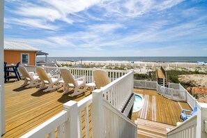 Relax on the deck with lounge chairs and a table, overlooking the ocean and sandy beach.