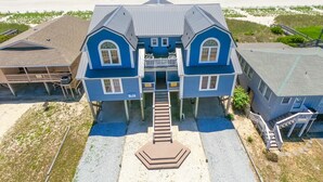 A large blue house with a balcony, located near a beach.