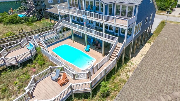 A multi-story house with a large deck and a swimming pool.