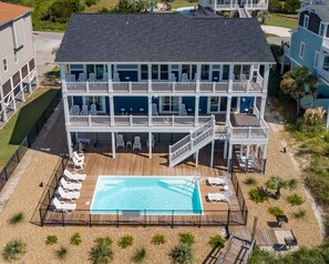 Un edificio de dos pisos con piscina, mobiliario exterior y terraza cubierta.