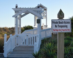 A wooden boardwalk leading to a white gazebo with a sign indicating private beach access and no trespassing for Tide Ridge Drive properties.
