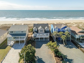 Um imóvel à beira-mar com várias casas, uma praia de areia e o oceano ao fundo.