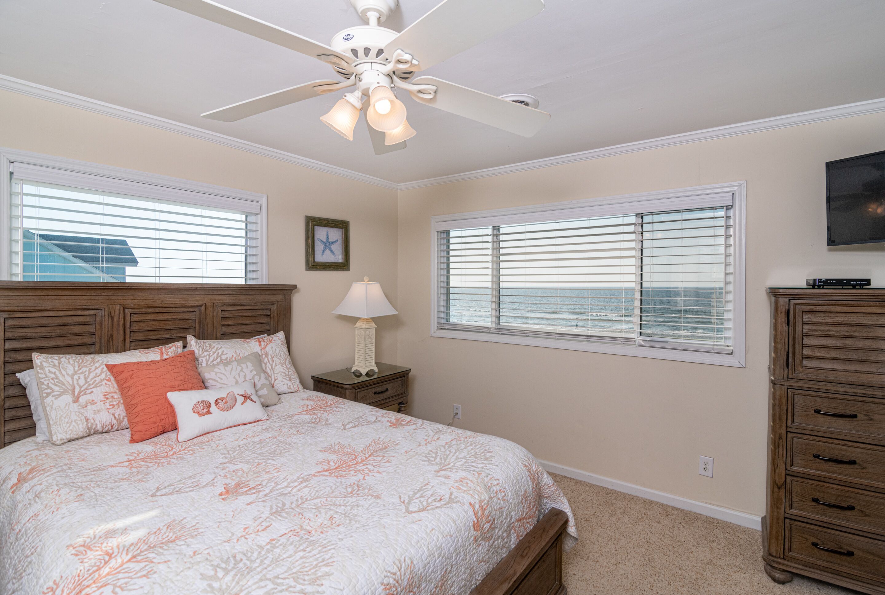 A bedroom with a bed, nightstands, a ceiling fan, and a dresser.