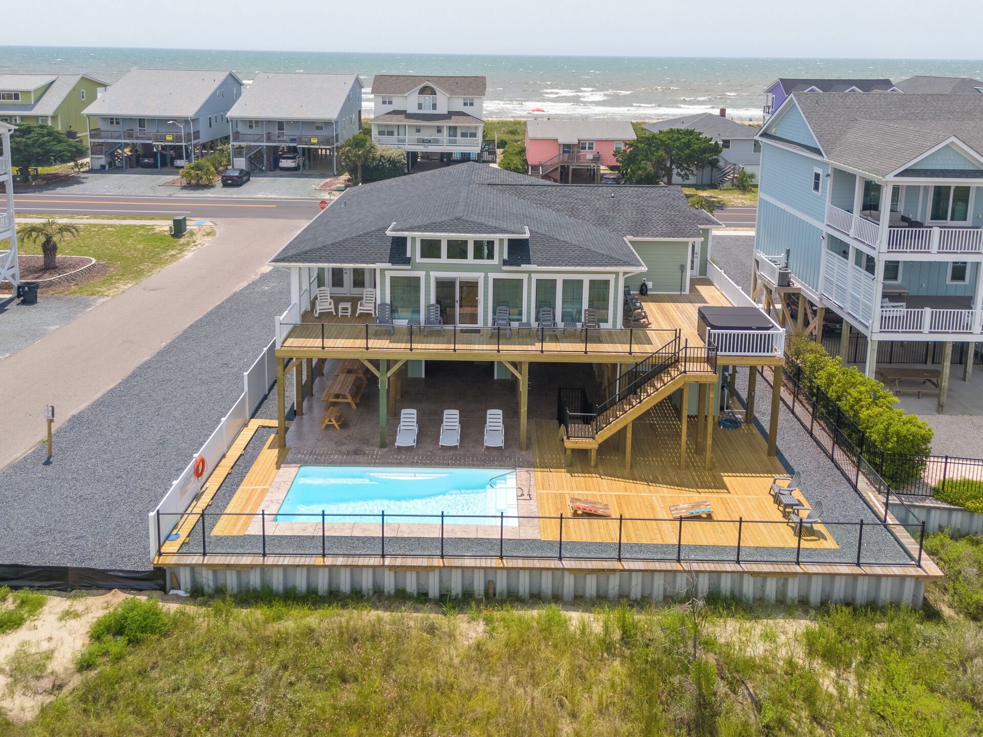En ejendom ved stranden med en stor pool, udendørs møbler og en overdækket terrasse.