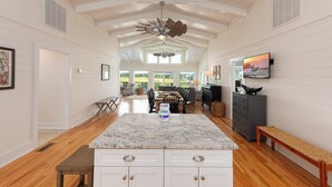 A spacious kitchen with a marble countertop, white cabinetry, and a central island.