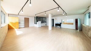 A spacious living area with a kitchen, a dining area, and a large window providing natural light. - Ganghwa Haemolupension (Incheon)