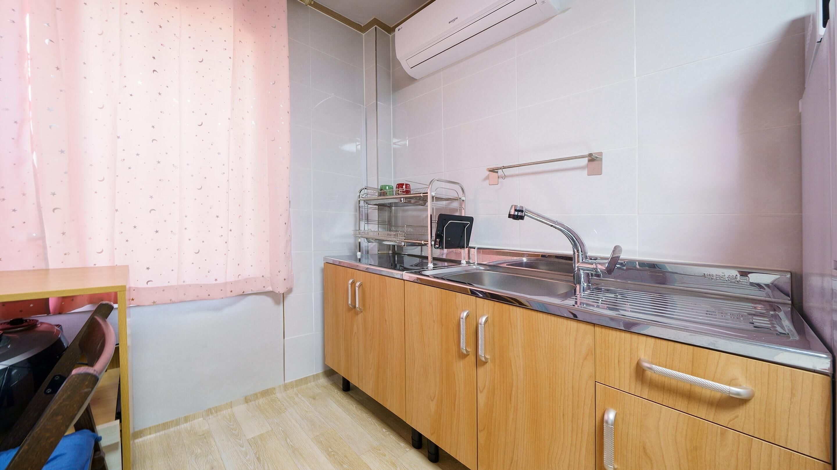 Una cocina con un lavamanos de acero inoxidable, armarios de madera y salpicadero de azulejos.
