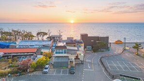 A coastal town with a parking area, buildings, and a view of the sunset over the sea. - Ganghwa Haemolupension (Incheon)