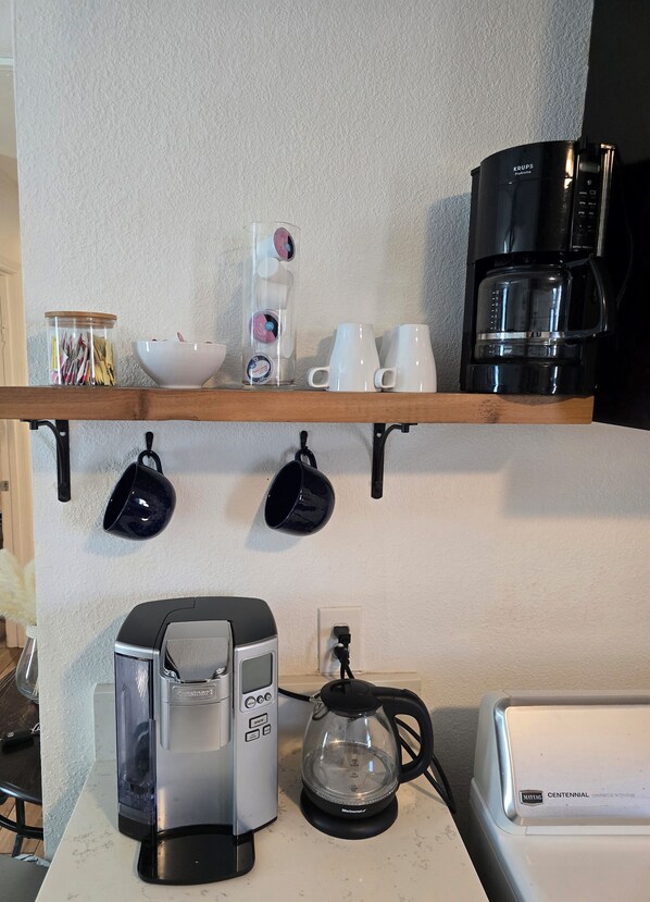 Une cuisine équipée d’une machine à café, d’une bouilloire et d’une cafetière sur le plan de travail.
