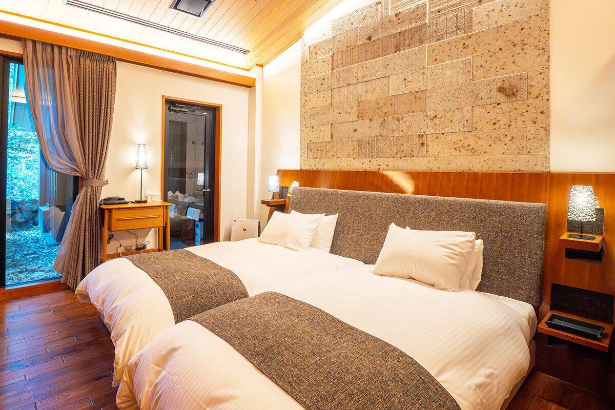 A double bed with a headboard, bedside tables, a lamp, and a view of the outdoors.
