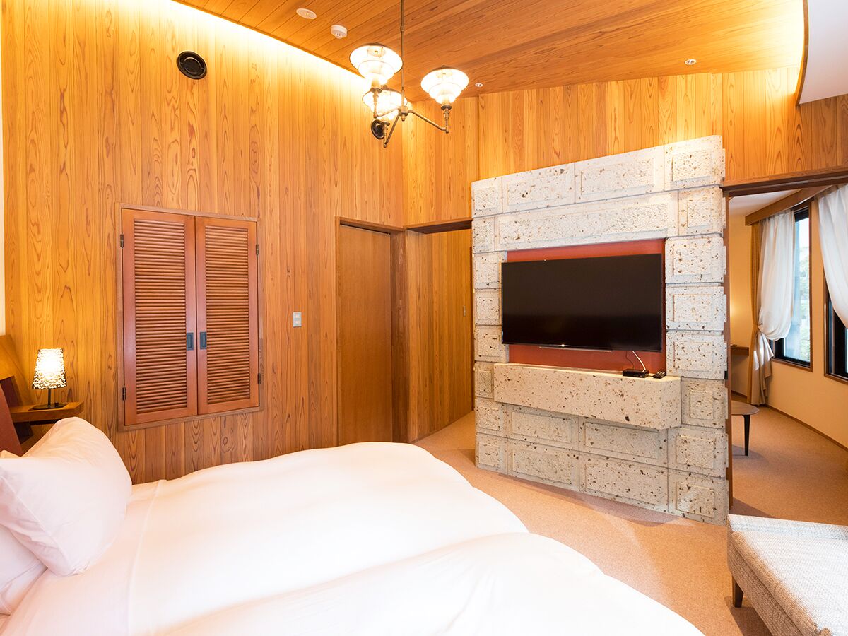 Een slaapkamer met een open haard van baksteen, houten wanden en een bed met witte lakens.