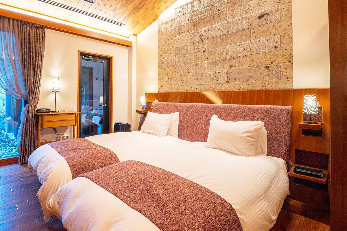A double bed with a wooden headboard, a nightstand with a lamp, and a large abstract wall art piece.