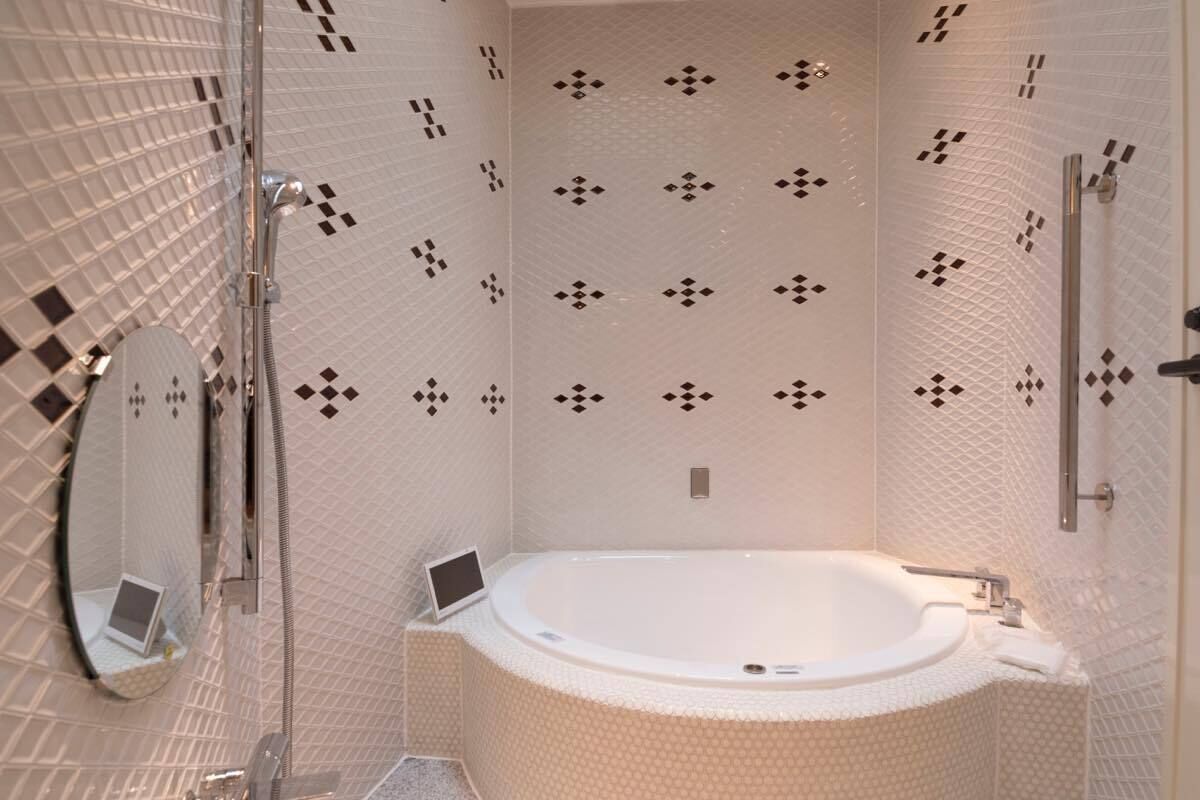 A modern bathroom with a freestanding bathtub, a handheld showerhead, and a wall-mounted toilet.