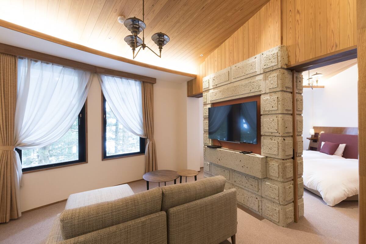 A hotel room with a stone fireplace, a television, a sofa, and a bed.
