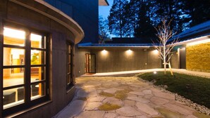 A modern building with large windows, a stone pathway, and a small tree. - NIKKO-NISHIMACHICLUB A LA TOUTO (Nikko)