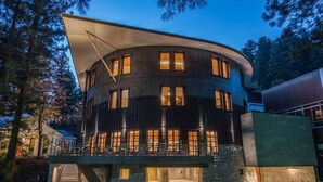 A modern building with a curved facade, multiple windows, and a stone base. - NIKKO-NISHIMACHICLUB A LA TOUTO (Nikko)