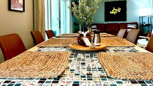 A dining area with a long table, woven placemats, and a vase with flowers. - Amazing Beachfront view and access! Pool & hot tub (South Padre Island)