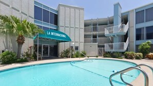 A swimming pool with a shark silhouette, a building labeled 'LA INTERNACIONAL,' and a covered patio area. - Amazing Beachfront view and access! Pool & hot tub (South Padre Island)